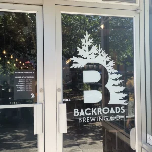 white cut vinyl logo sign and lettering applied to the glass door of the entrance to a brewery
