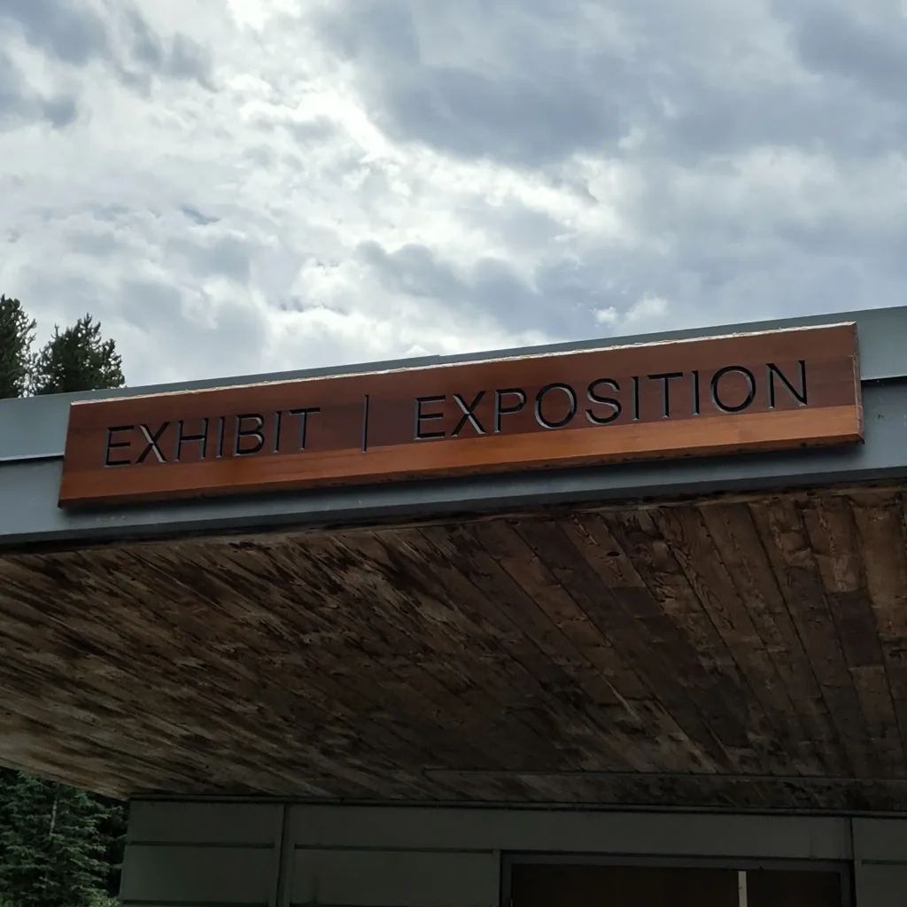 A wood sign that says exhibit, exposition at a museum