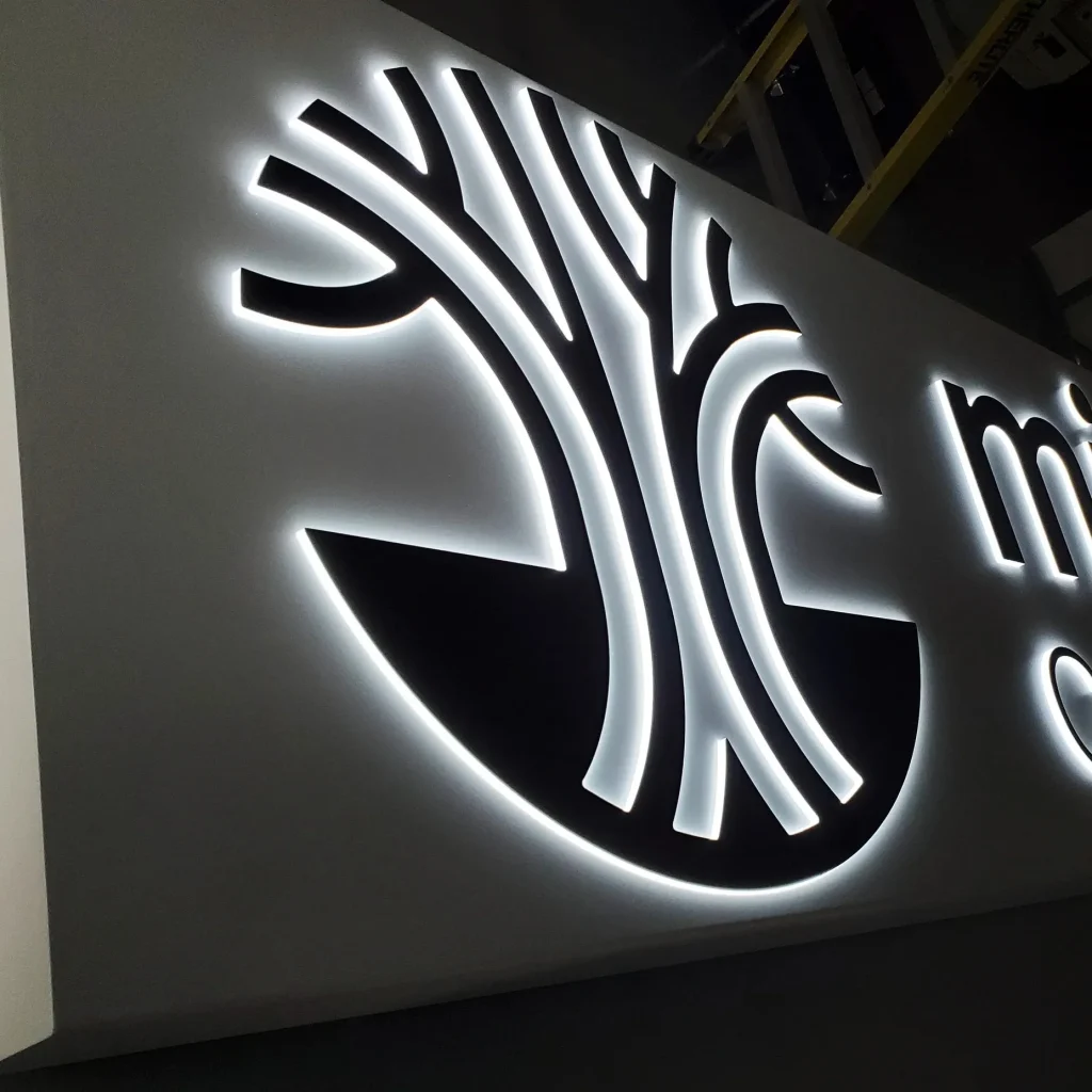 Black push thru logo with white halo lighting installed on white sign box.