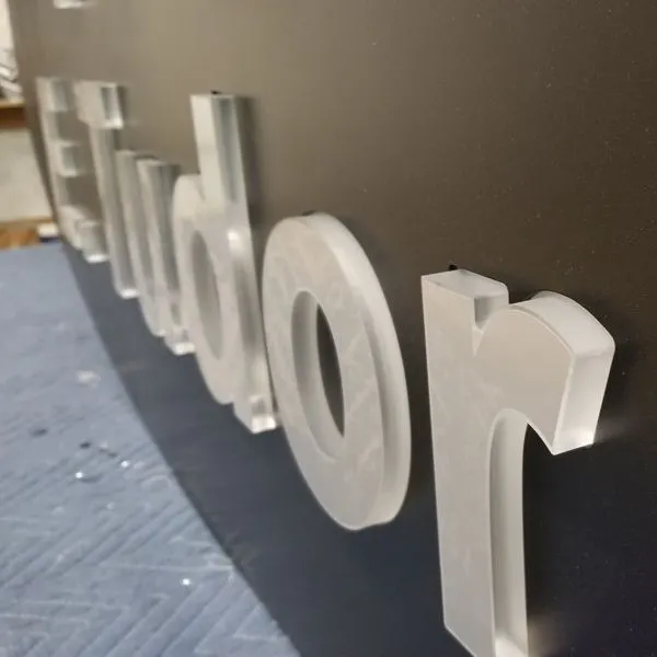 Acrylic letters pushed through cut outs on a sign box.