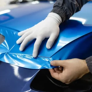 Close up of a man installing vinyl on a car.